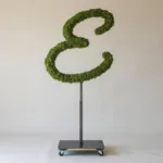 Monogram letter E topiary in Flowing script style, packed with green moss, on an adjustable stand