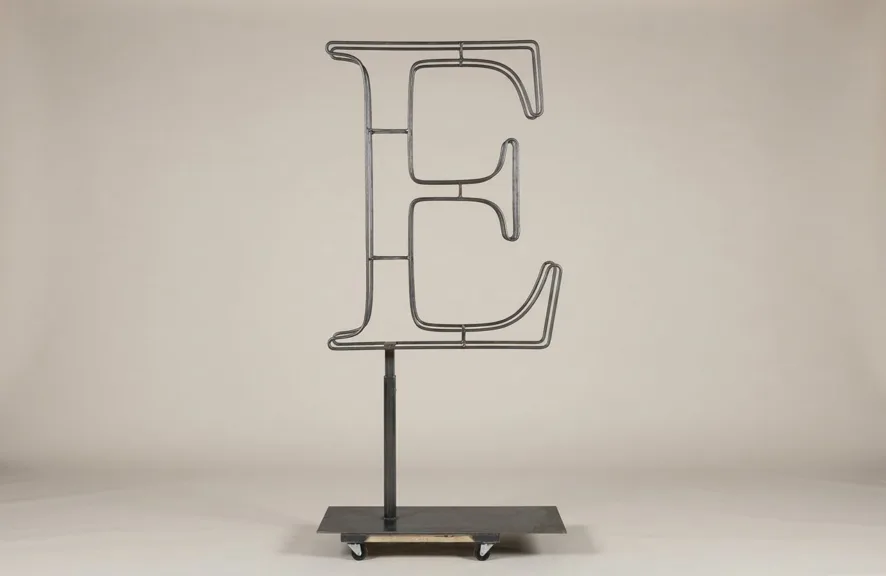 Monogram letter E topiary frame in Roman style, bare galvanized steel on an adjustable stand