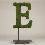 Monogram letter E topiary in Roman style, packed with green moss, on an adjustable stand