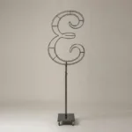 Monogram letter E topiary frame in Script style, bare galvanized steel on an adjustable stand