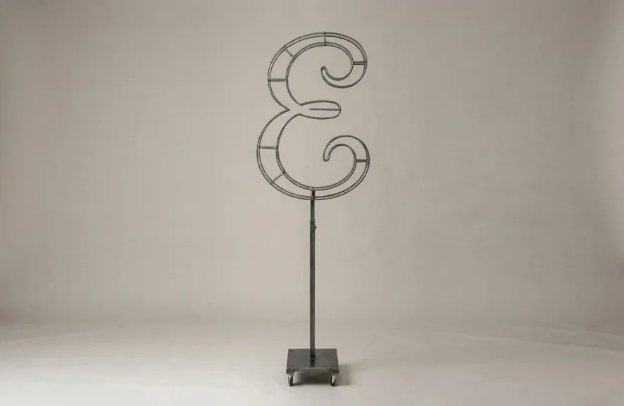 Monogram letter E topiary frame in Script style, bare galvanized steel on an adjustable stand