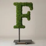Monogram letter F topiary in Cinzel style, packed with green moss, on an adjustable stand