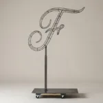 Monogram letter F topiary frame in Flowing script style, bare galvanized steel on an adjustable stand