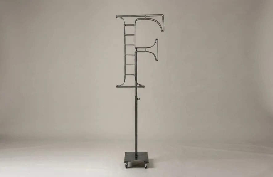 Monogram letter F topiary frame in Roman style, bare galvanized steel on an adjustable stand
