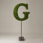 Monogram letter G topiary in Cinzel style, packed with green moss, on an adjustable stand