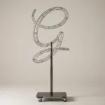 Monogram letter G topiary frame in Flowing script style, bare galvanized steel on an adjustable stand