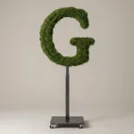 Monogram letter G topiary in Roman style, packed with green moss, on an adjustable stand