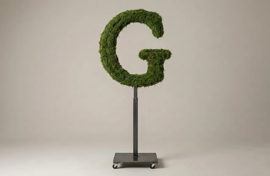 Monogram letter G topiary in Roman style, packed with green moss, on an adjustable stand