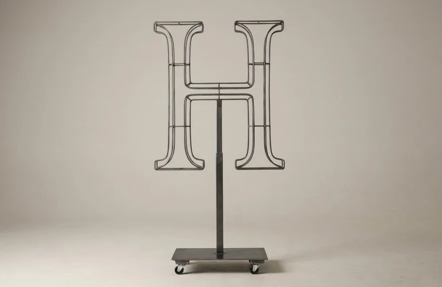 Monogram letter H topiary frame in Cinzel style, bare galvanized steel on an adjustable stand