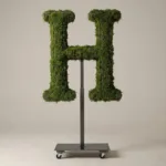 Monogram letter H topiary in Cinzel style, packed with green moss, on an adjustable stand