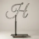 Monogram letter H topiary frame in Flowing script style, bare galvanized steel on an adjustable stand