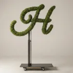 Monogram letter H topiary in Flowing script style, packed with green moss, on an adjustable stand