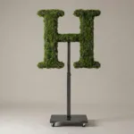 Monogram letter H topiary in Roman style, packed with green moss, on an adjustable stand