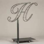 Monogram letter H topiary frame in Script style, bare galvanized steel on an adjustable stand
