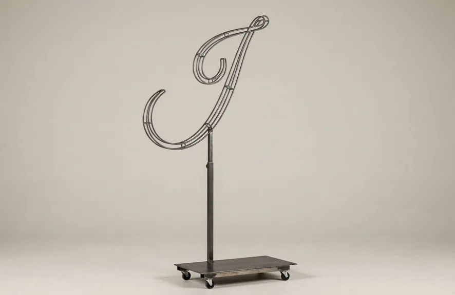 Monogram letter I topiary frame in Flowing script style, bare galvanized steel on an adjustable stand