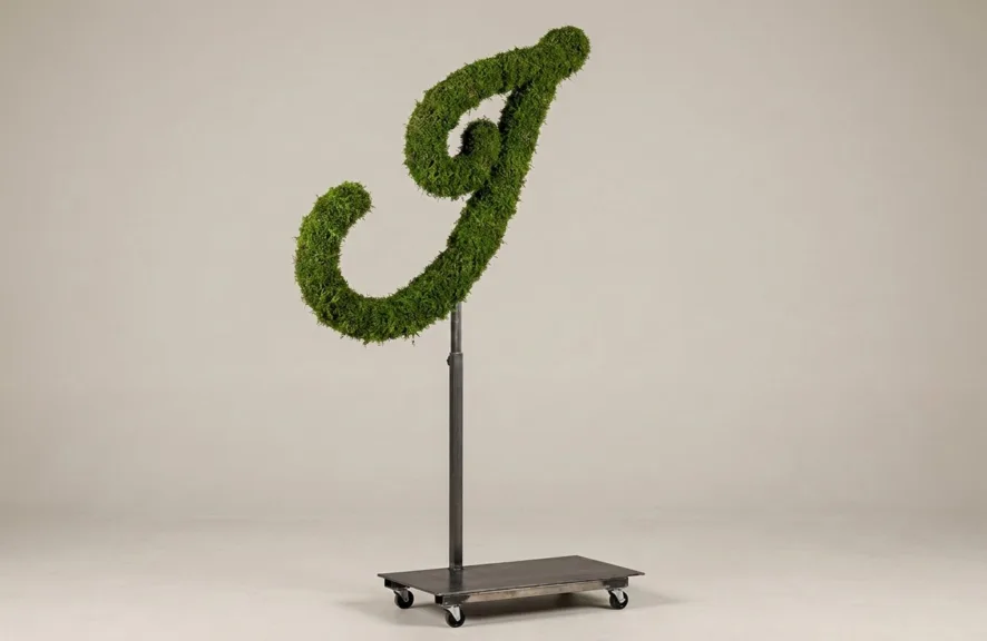 Monogram letter I topiary in Flowing script style, packed with green moss, on an adjustable stand