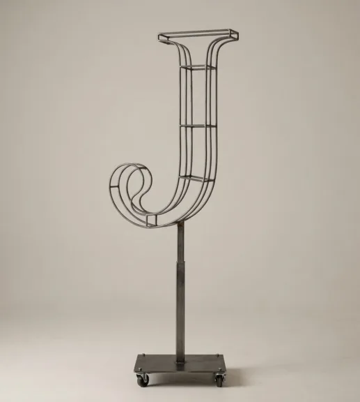Monogram letter J topiary frame in Cinzel style, bare galvanized steel on an adjustable stand