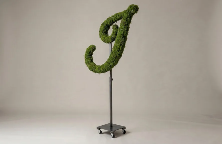 Monogram letter J topiary in Flowing script style, packed with green moss, on an adjustable stand