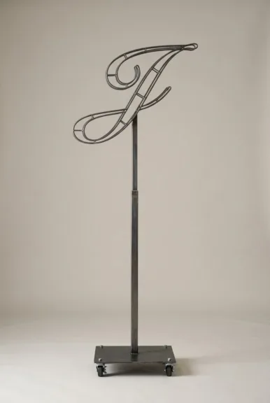 Monogram letter J topiary frame in Script style, bare galvanized steel on an adjustable stand
