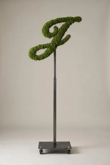 Monogram letter J topiary in Script style, packed with green moss, on an adjustable stand