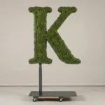Monogram letter K topiary in Cinzel style, packed with green moss, on an adjustable stand