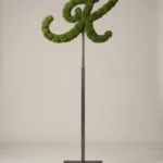 Monogram letter K topiary in Flowing script style, packed with green moss, on an adjustable stand
