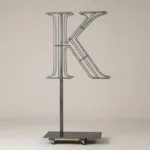 Monogram letter K topiary frame in Roman style, bare galvanized steel on an adjustable stand