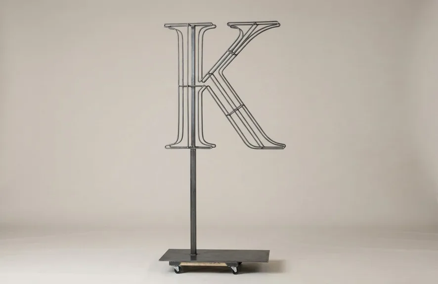 Monogram letter K topiary frame in Roman style, bare galvanized steel on an adjustable stand