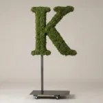 Monogram letter K topiary in Roman style, packed with green moss, on an adjustable stand