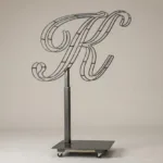 Monogram letter K topiary frame in Script style, bare galvanized steel on an adjustable stand