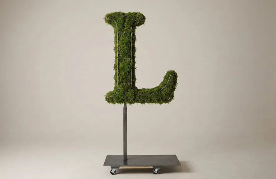 Monogram letter L topiary in Cinzel style, packed with green moss, on an adjustable stand