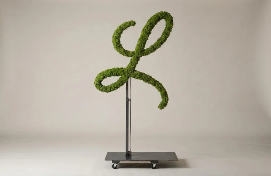 Monogram letter L topiary in Flowing script style, packed with green moss, on an adjustable stand