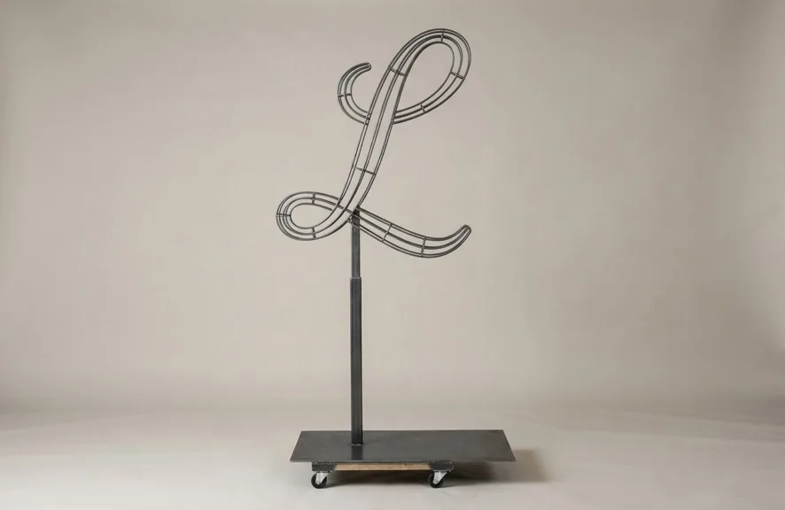 Monogram letter L topiary frame in Script style, bare galvanized steel on an adjustable stand