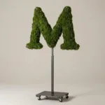 Monogram letter M topiary in Cinzel style, packed with green moss, on an adjustable stand