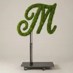 Monogram letter M topiary in Flowing script style, packed with green moss, on an adjustable stand