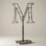 Monogram letter M topiary frame in Roman style, bare galvanized steel on an adjustable stand