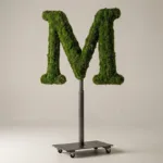Monogram letter M topiary in Roman style, packed with green moss, on an adjustable stand
