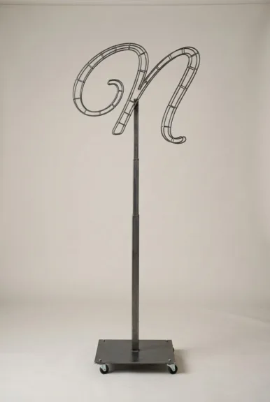 Monogram letter N topiary frame in Flowing script style, bare galvanized steel on an adjustable stand