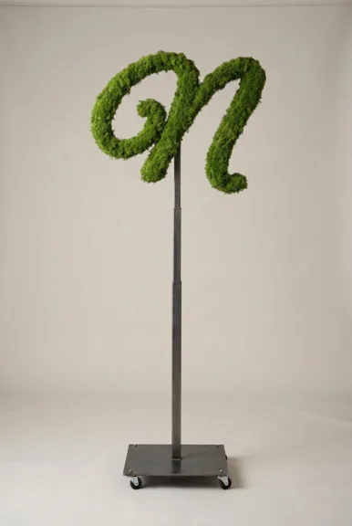 Monogram letter N topiary in Flowing script style, packed with green moss, on an adjustable stand