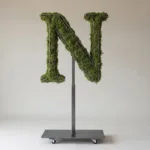 Monogram letter N topiary in Roman style, packed with green moss, on an adjustable stand