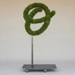 Monogram letter O topiary in Flowing script style, packed with green moss, on an adjustable stand