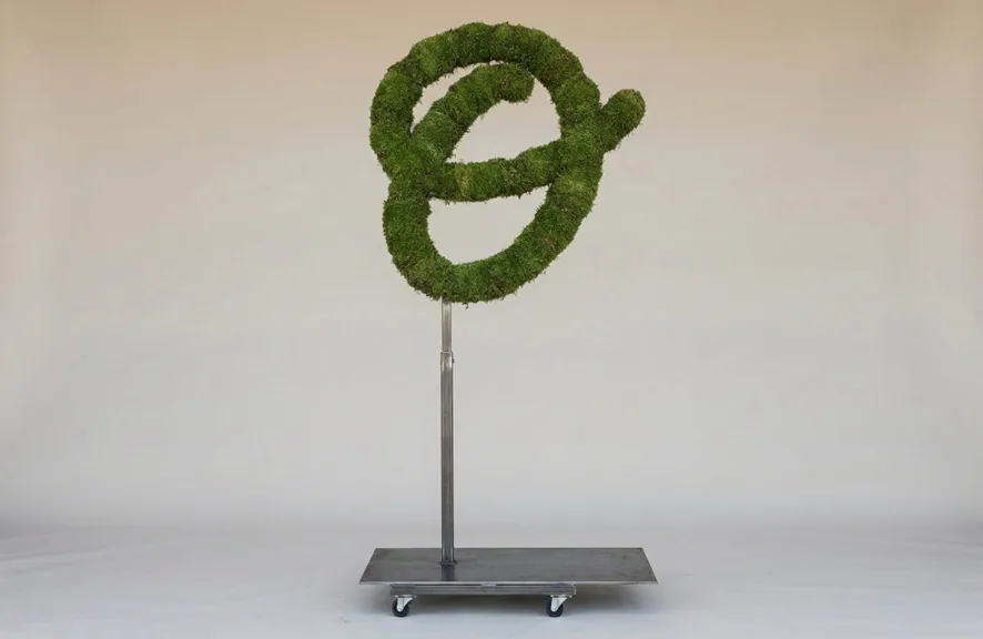 Monogram letter O topiary in Flowing script style, packed with green moss, on an adjustable stand
