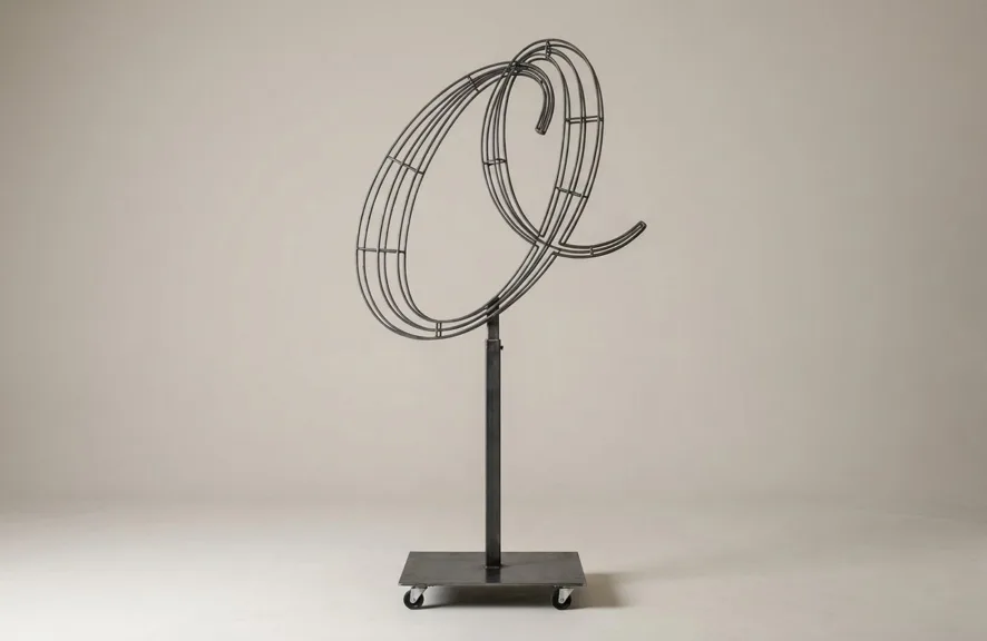 Monogram letter O topiary frame in Script style, bare galvanized steel on an adjustable stand