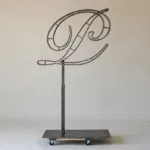 Monogram letter P topiary frame in Script style, bare galvanized steel on an adjustable stand