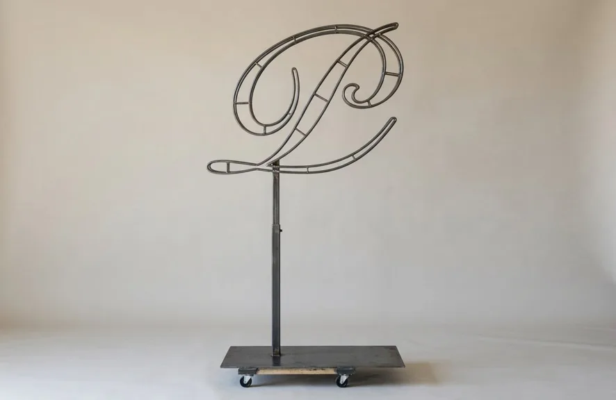 Monogram letter P topiary frame in Script style, bare galvanized steel on an adjustable stand
