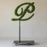 Monogram letter P topiary in Script style, packed with green moss, on an adjustable stand