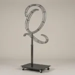 Monogram letter Q topiary frame in Flowing script style, bare galvanized steel on an adjustable stand
