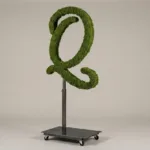 Monogram letter Q topiary in Flowing script style, packed with green moss, on an adjustable stand