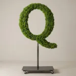 Monogram letter Q topiary in Roman style, packed with green moss, on an adjustable stand