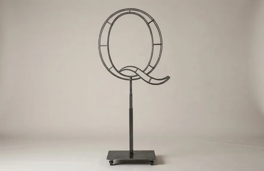 Monogram letter Q topiary frame in Script style, bare galvanized steel on an adjustable stand
